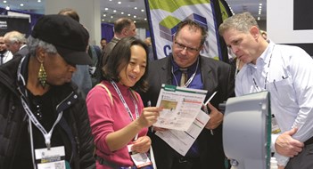 A group of people gather around to examine a data sheet at the Cooperator Events Expo 