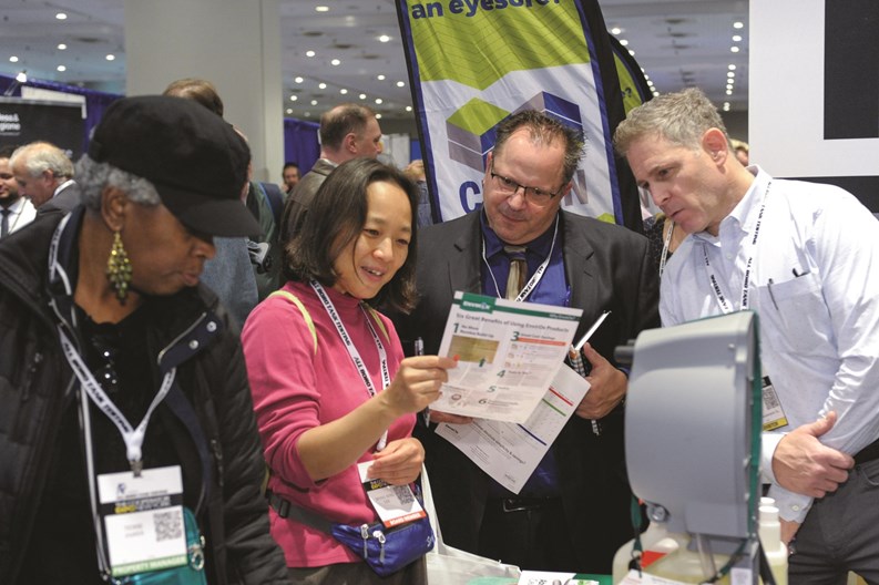 A group of people gather around to examine a data sheet at the Cooperator Events Expo 