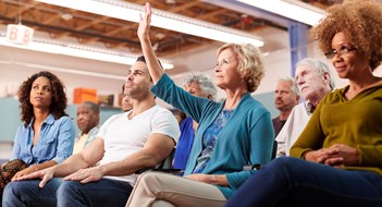 Woman Asking Question At Neighborhood Meeting In Community Center