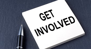 Increasing Board Involvement GET INVOLVED text on sticker with pen on black background