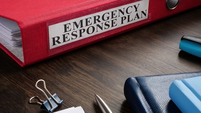 A Red folder with Emergency response plan on the desk.