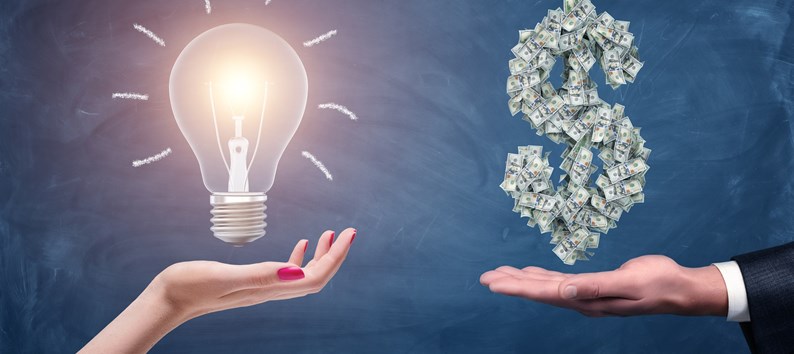 A female and a male hands holding a large bright light bulb and a dollar sign made of many money bills. Money and wealth. Profitable ideas. Financial streak.