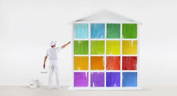 Aesthetic Rules rear view of painter man pointing with finger the colors house model on wall, with paint roller and bucket, isolated on white
