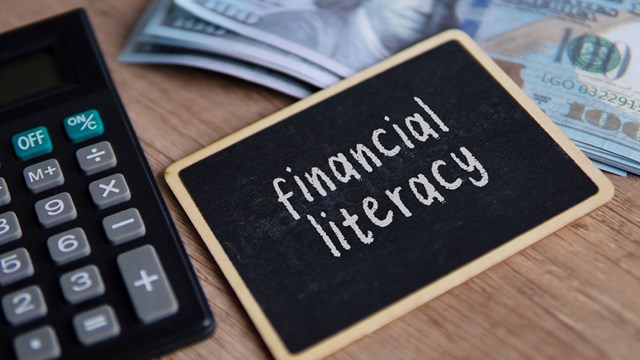 Top view image of piggy bank, calculator and money with text FINANCIAL LITERACY.