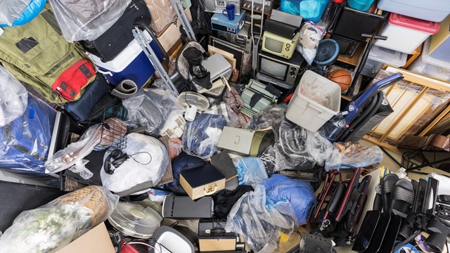Hoarder house junk pile of clothing bags, household objects, vintage electronics and miscellaneous objects.