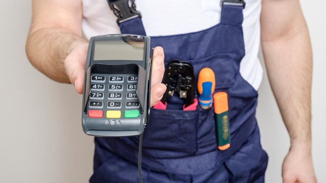 Man with tools holding bank payment terminal. Salary concept