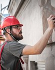 Man worker standing on scaffolding, perform work on the restoration of the facade of the old building. Repairing and renovate
