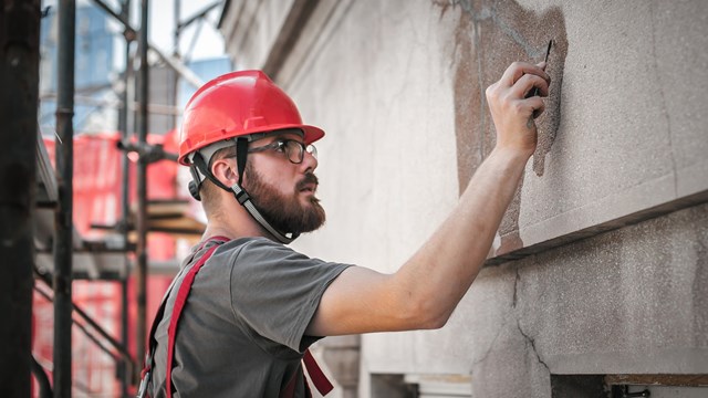 Man worker standing on scaffolding, perform work on the restoration of the facade of the old building. Repairing and renovate
