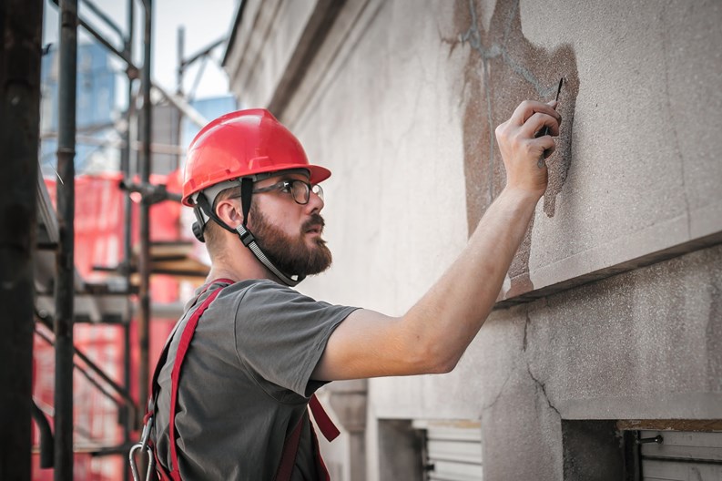 Man worker standing on scaffolding, perform work on the restoration of the facade of the old building. Repairing and renovate