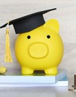 Graduation hat on piggy bank with stack of coins money on wooden background, Saving money for education concept