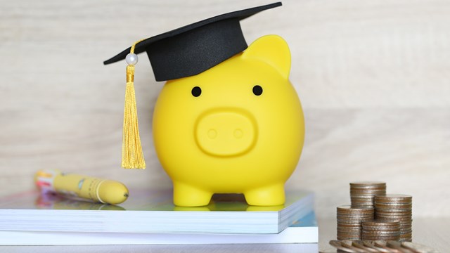 Graduation hat on piggy bank with stack of coins money on wooden background, Saving money for education concept