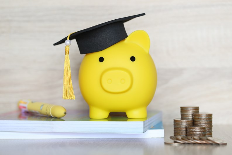 Graduation hat on piggy bank with stack of coins money on wooden background, Saving money for education concept