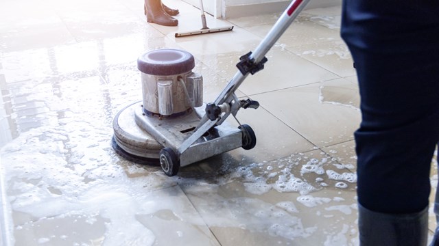 Janitor use floor scrubber machine on the floor hallway office building or walkway after school and classroom work job with sun light background. Wet floor or cleaning service house maid concept.