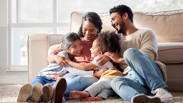 Affectionate and loving mixed race family sitting together. Happy family with two daughters hugging their mother and bonding at home. Two little girls enjoying a happy childhood with mom and dad