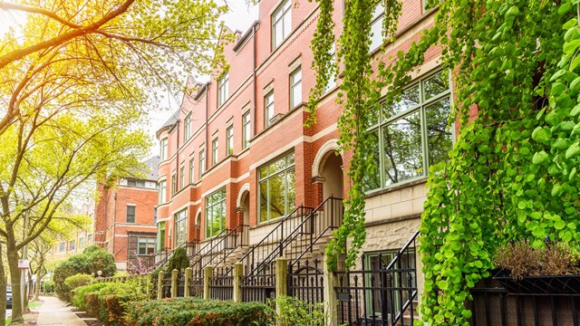 Row of modern brick town houses along a tree lined sidewalk in a residential district on a sunny spring day. Chicago, IL, USA.