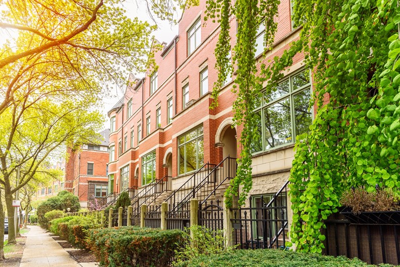 Row of modern brick town houses along a tree lined sidewalk in a residential district on a sunny spring day. Chicago, IL, USA.