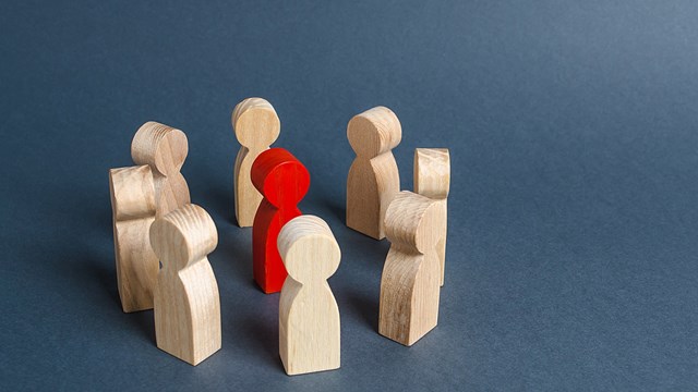 Red human figure surrounded by a circle of people. Leader Boss and leadership. Cooperation and teamwork. Outcast, hated opponent, criminal. Conviction. Discrimination and violence.