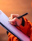 Safety officer/Supervisor is writing note on the checklist paper during perform audit and inspection in oil field operation. Close-up action and selective focus photo.