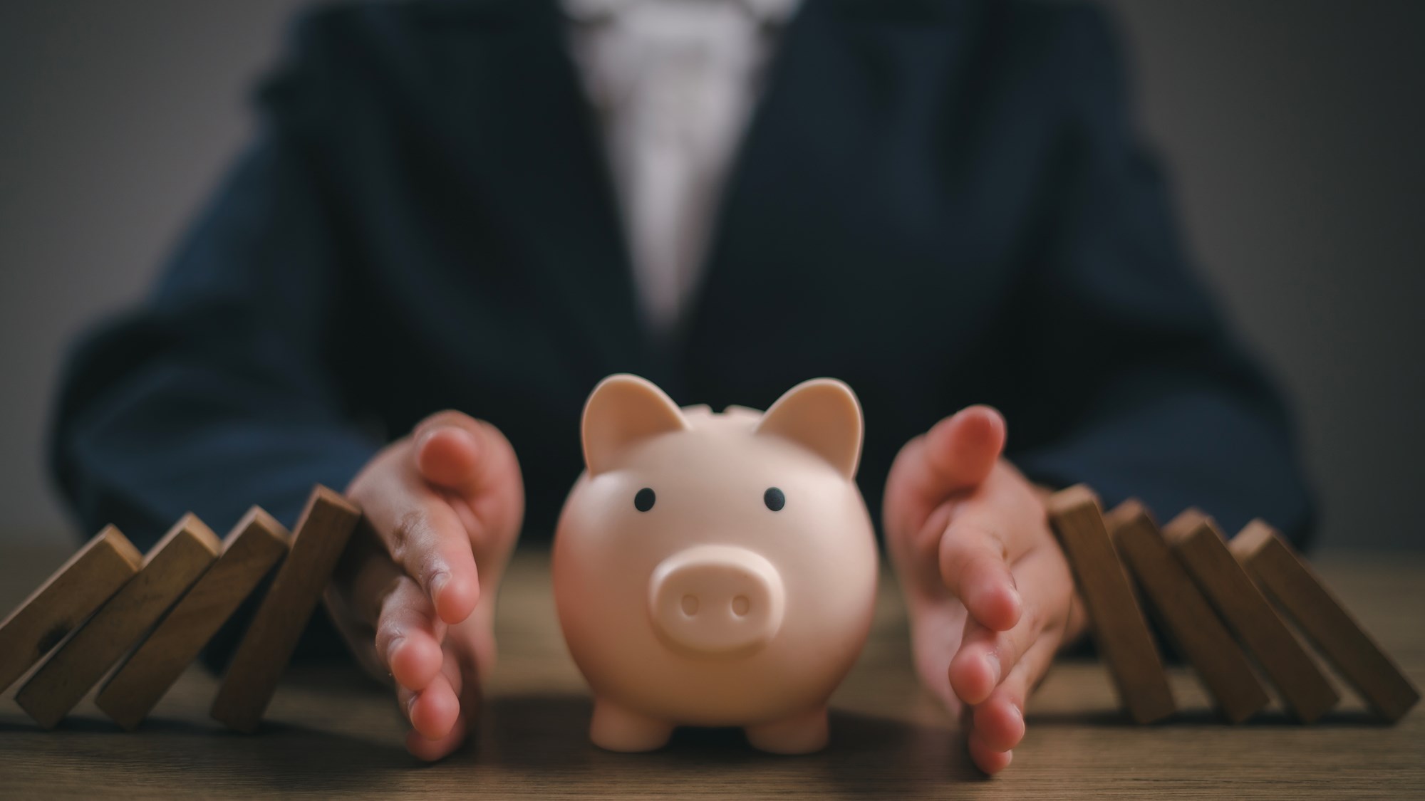 Businesswoman placed a wooden block on a piggy bank. stop the domino crisis effect, financial and banking problems, recession, financial crisis, bad debt, inflation and interest rates, asset safety
