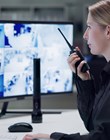 Watch, security and woman with radio, cctv and monitor for danger, talking and control room for guard. Desk, night and working for protection, safety and communication to backup and connection