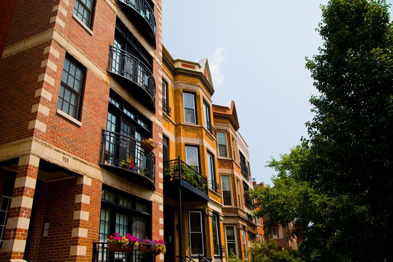Upscale Urban Living in Chicago: A picturesque row of red brick buildings with modern and traditional architectural details, showcasing luxury apartments and a vibrant city lifestyle.